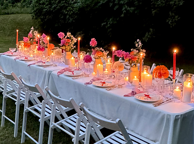 Table de jardin dressée au crépuscule, bougies, fleurs colorées et chaises blanches - Table by At Home With Soni